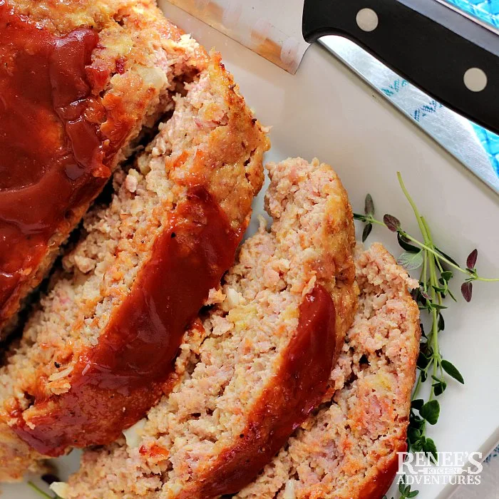 Amish Ham Loaf on white platter, sliced, with fresh thyme garnish