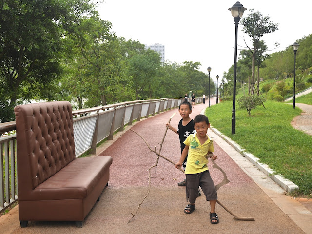 two boys holding large tree branches in Ganzhou