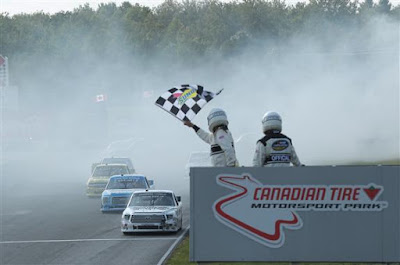 he starter waves the checkered flag as Harrison Burton (#51) prepares to cross the finish line at Canadian Tire Mosport Park