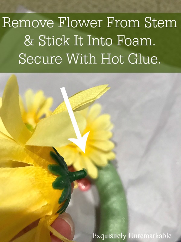 Yellow flower stem with arrow pointing to where you should apply glue before adding it to wreath