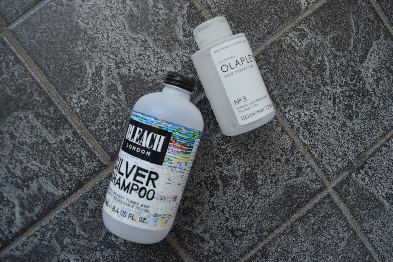 Bleach London Silver Shampoo and Olaplex no 3 on a tiled floor
