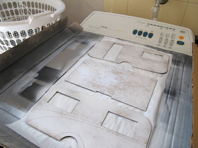 Spray-painted pieces of a 1/12 scale retro caravan kit, laid out to dry on top of a washing machine.