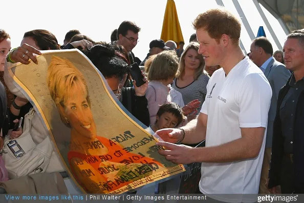Prince Harry looks at a photo of his mother, Princess Diana shown by Faasiu Gaee from Samoa as he meets members of the public at an event to promote the 2015 FIFA U-20 World Cup which will be hosted by New Zealand