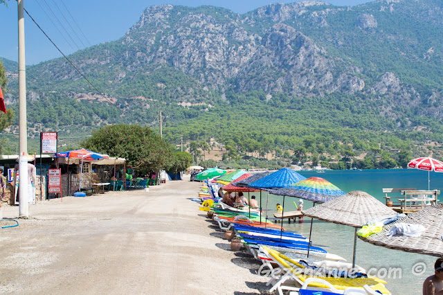 Akbük plajında deniz kıyısı boyunca dizili şezlong ve şemsiyeler, Akyaka