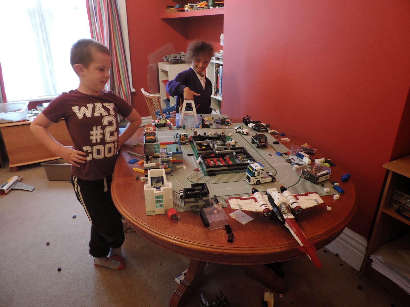 boy and girl showing off lego construction lego city star wars fighter on dining table