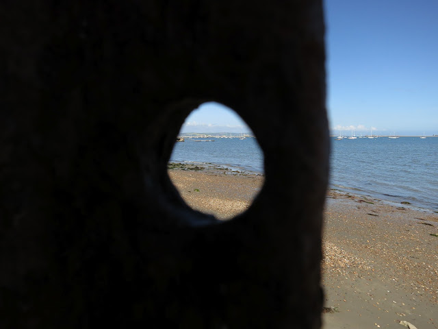 Sea and beach seen both through a metal hole and not.