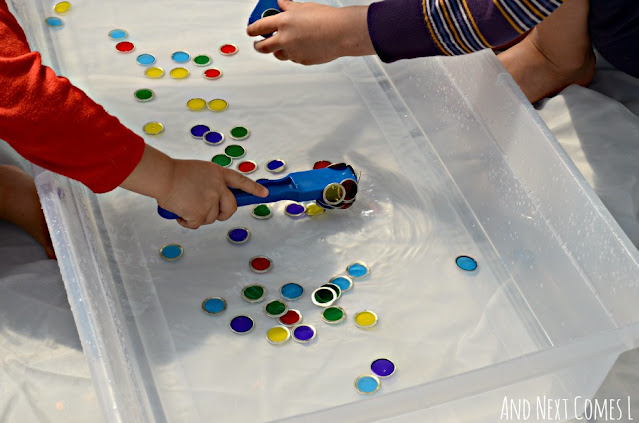Child fishing for colorful magnets in a water sensory bin