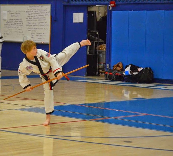 a young black belt doing a side kick