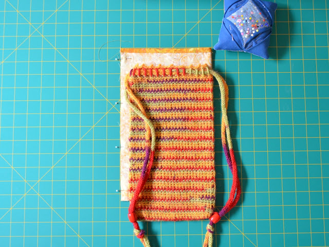 A comparison of the folded fabric and the bag widths to double check the seam allowance.  The pincushion can be seen towards the top of the picture.