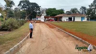 Acertando a terra para a execução da rua com o calçamento com pedras tipo de piso com pedrisco compactado com as guias de pedra, com pedra folheta, em rua da entrada da sede da fazenda em Atibaia-SP e a execução do paisagismo.