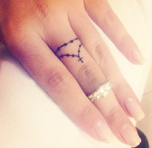 Mano de una chica mostrando su tatuaje en forma de rosario que está en el dedo medio