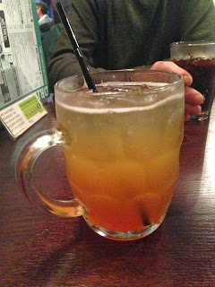 a strange looking orange drink in a pint glass