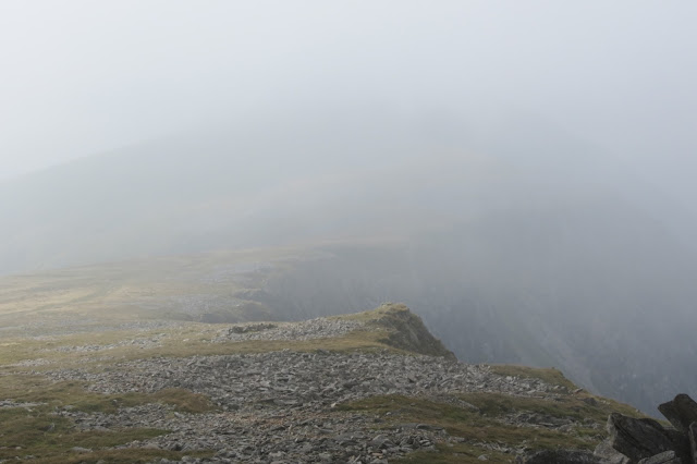 A line of cliffs at the edge of the plateau disappearing into mist.