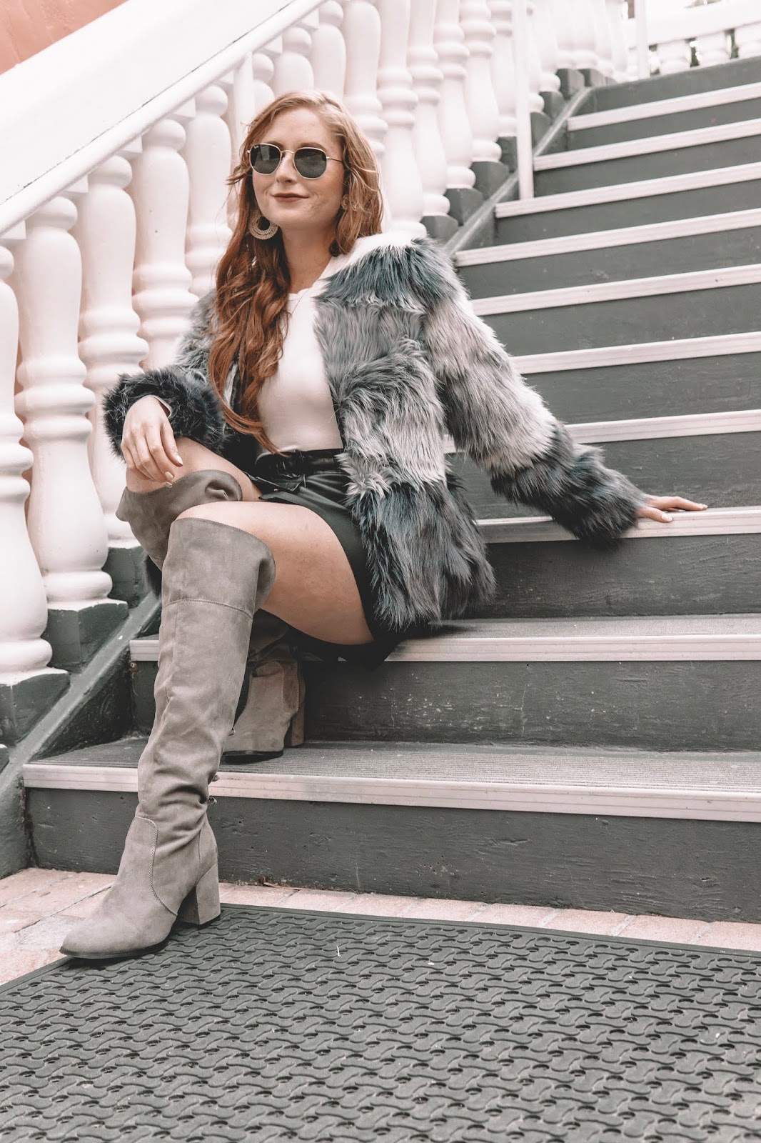 Tampa blogger Amanda Burrows is wearing an ombre faux fur jacket standing at the Don CeSar Hotel. She is wearing gray over the knee boots and a leather skirt from ASOS. She is also wearing Chesnut extensions from Barefoot Blonde Hair.