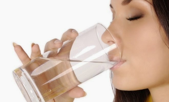 Slika prikazuje kozarec z vodo in žensko ki pije z njega - Lepa koža se dela spomladi
