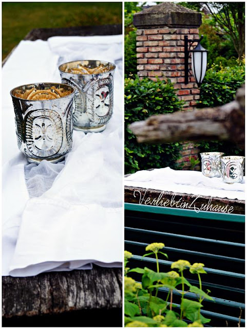 Windlicht, Teelichthalter aus Glas mit Bauernsilber. Im Garten hübsch dekoriert auf rustikalem Holztisch
