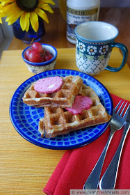 image of a plate of waffles topped with cranberry honey butter, served with a side of grapes and a jug of maple syrup