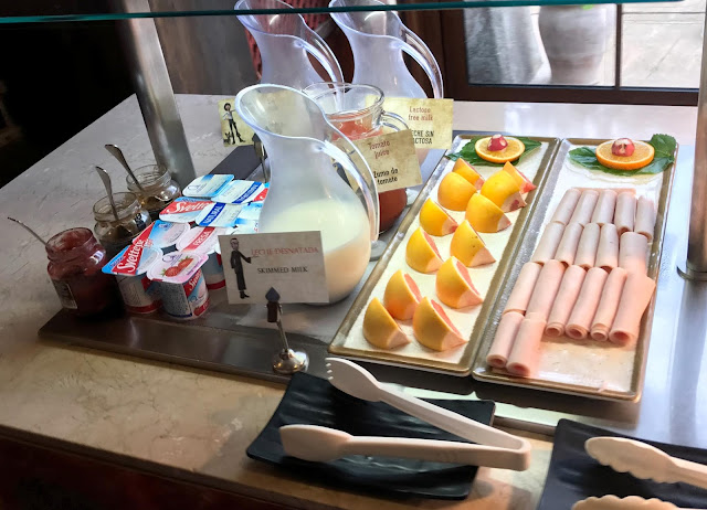 some breakfast items of grapefruit, meat, yogurts and drinks 