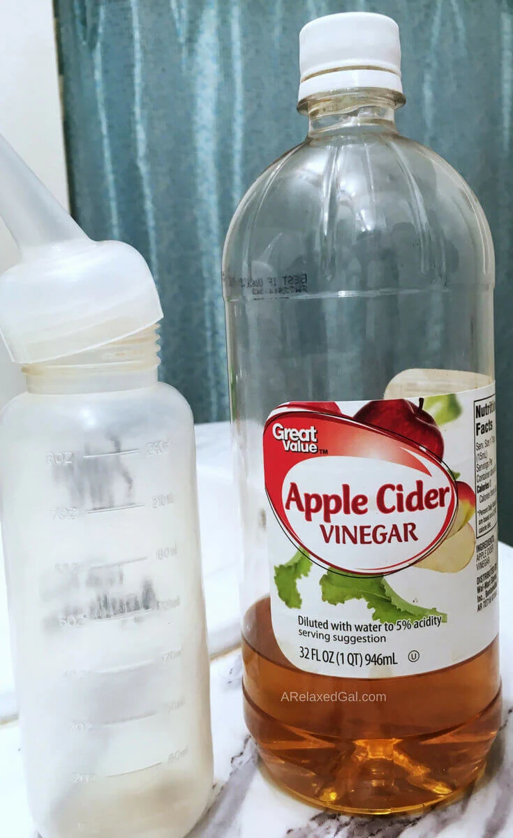 Bottle of apple cider vinegar and applicator bottle on a bathroom counter.