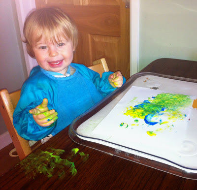 Child now looking pleased with himself - paint on table too!