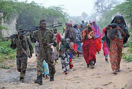 Somali woman and children are escorted in the rain by soldiers