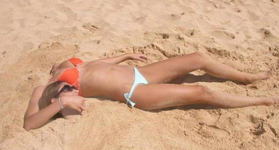 Banyak permainan yang bisa dilakukan dengan pasir pantai. Salah satu yang paling populer adalah mengubur diri. Persis seperti yang dilakukan wanita di atas. Nah, hebatnya sekilas kepala wanita itu tampak terpisah :)