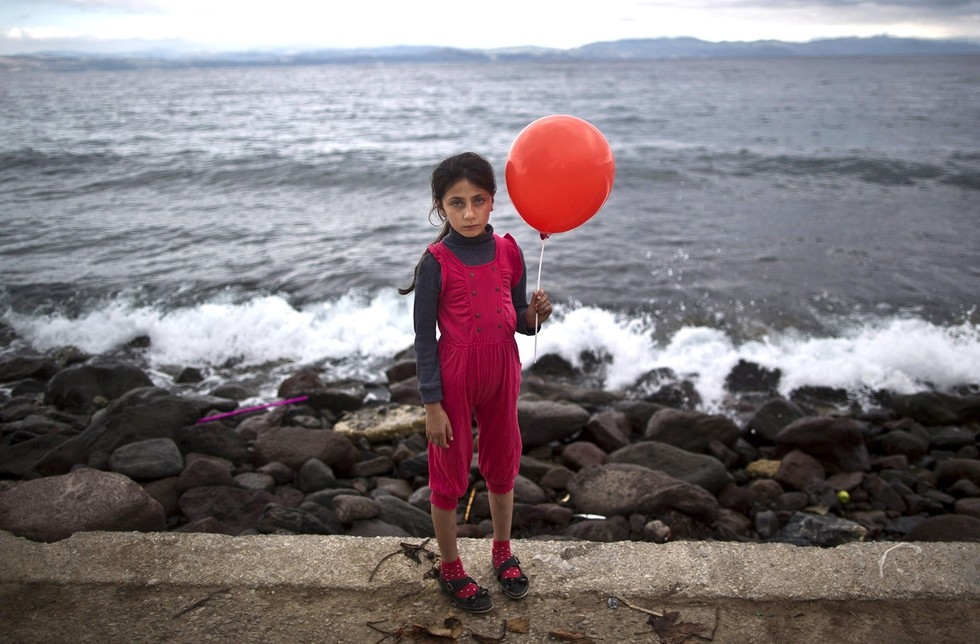 70 Of The Most Touching Photos Taken In 2015 - An exhausted Raghad Faleh, 8, poses for a photo while holding a balloon given to her by volunteers. A few hours earlier, she had arrived in Greece by dingy.