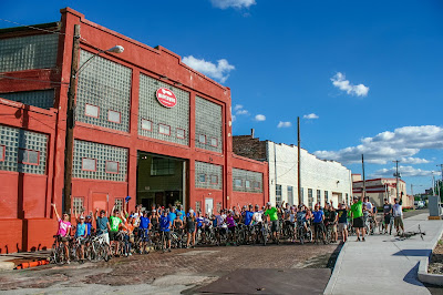 Photo of a large group of bicyclists in front of Warped Wing Brewing.