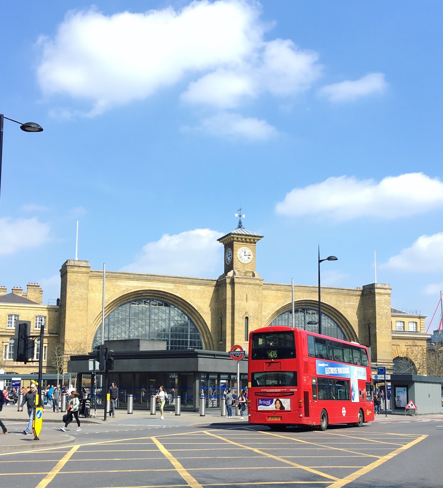 Kings Cross station can be seen, the sky is blue and a red double decker bus is visible.