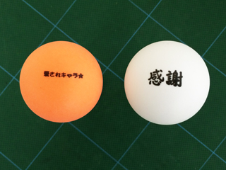 メッセージを印刷したオレンジ色と白のピンポン玉