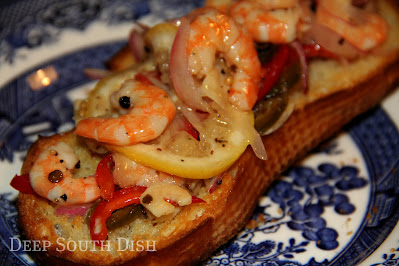 Boiled or sautéed shrimp, layered with paper thin strips of lemon, red onion, bell pepper, jalapeno, and garlic, whole bay leaves and dressed with a vinaigrette. Shown here on a slice of toasted bread.