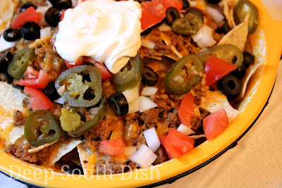 Layered tortilla chips, with seasoned ground beef, or leftover meats from your BBQ, cheese and topped with all of your favorite nacho toppings - chopped onion, tomatoes, pico, corn, jalapenos, black olives, sour cream, or choose your own favorite toppings.