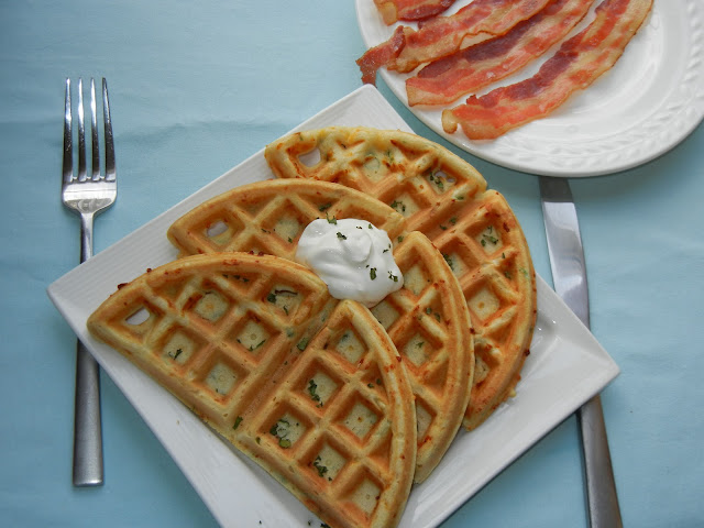 above photo of waffles on a plate with a dollop of sour cream and a fork to the left 