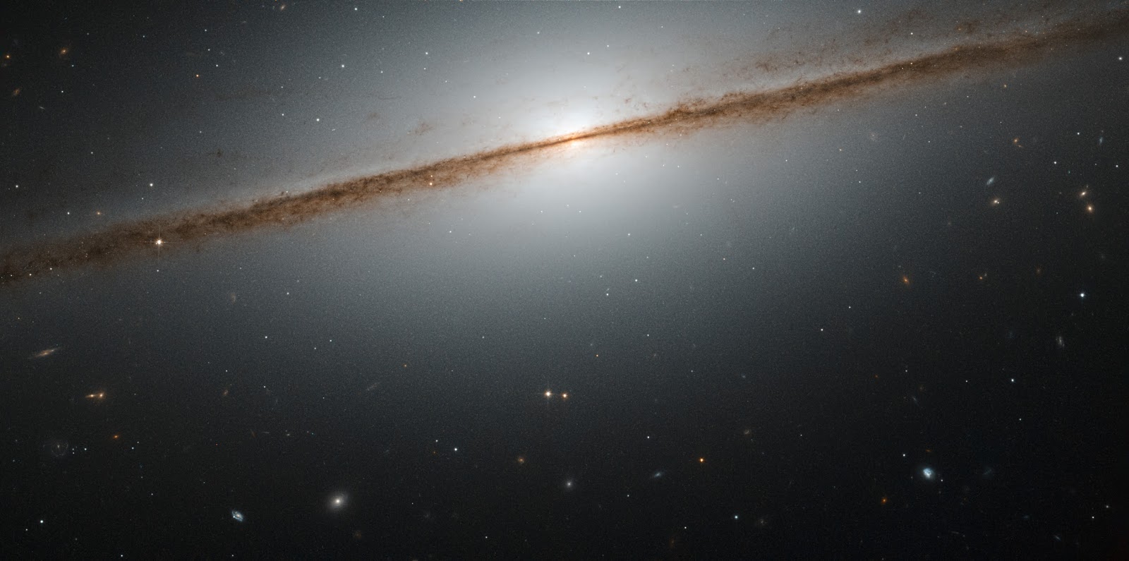 Hubble's Little Sombrero Hubble's Little Sombrero   Galaxies can take many shapes and be oriented any way relative to us in the sky. This can make it hard to figure out their actual morphology, as a galaxy can look very different from different viewpoints. A special case is when we are lucky enough to observe a spiral galaxy directly from its edge, providing us with a spectacular view like the one seen in this picture of the week.  This is NGC 7814, also known as the “Little Sombrero.” Its larger namesake, the Sombrero Galaxy, is another stunning example of an edge-on galaxy — in fact, the “Little Sombrero” is about the same size as its bright namesake at about 60,000 light-years across, but as it lies farther away, and so appears smaller in the sky.  NGC 7814 has a bright central bulge and a bright halo of glowing gas extending outwards into space. The dusty spiral arms appear as dark streaks. They consist of dusty material that absorbs and blocks light from the galactic center behind it. The field of view of this NASA/ESA Hubble Space Telescope image would be very impressive even without NGC 7814 in front; nearly all the objects seen in this image are galaxies as well.   Image Credit: ESA/Hubble, NASA & Josh Barrington Explanation from: http://www.nasa.gov/content/goddard/hubbles-little-sombrero/