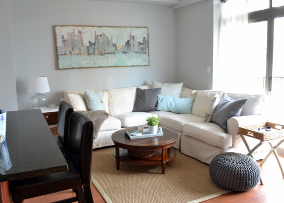 Family room with a white couch and skyline painting on the wall. 