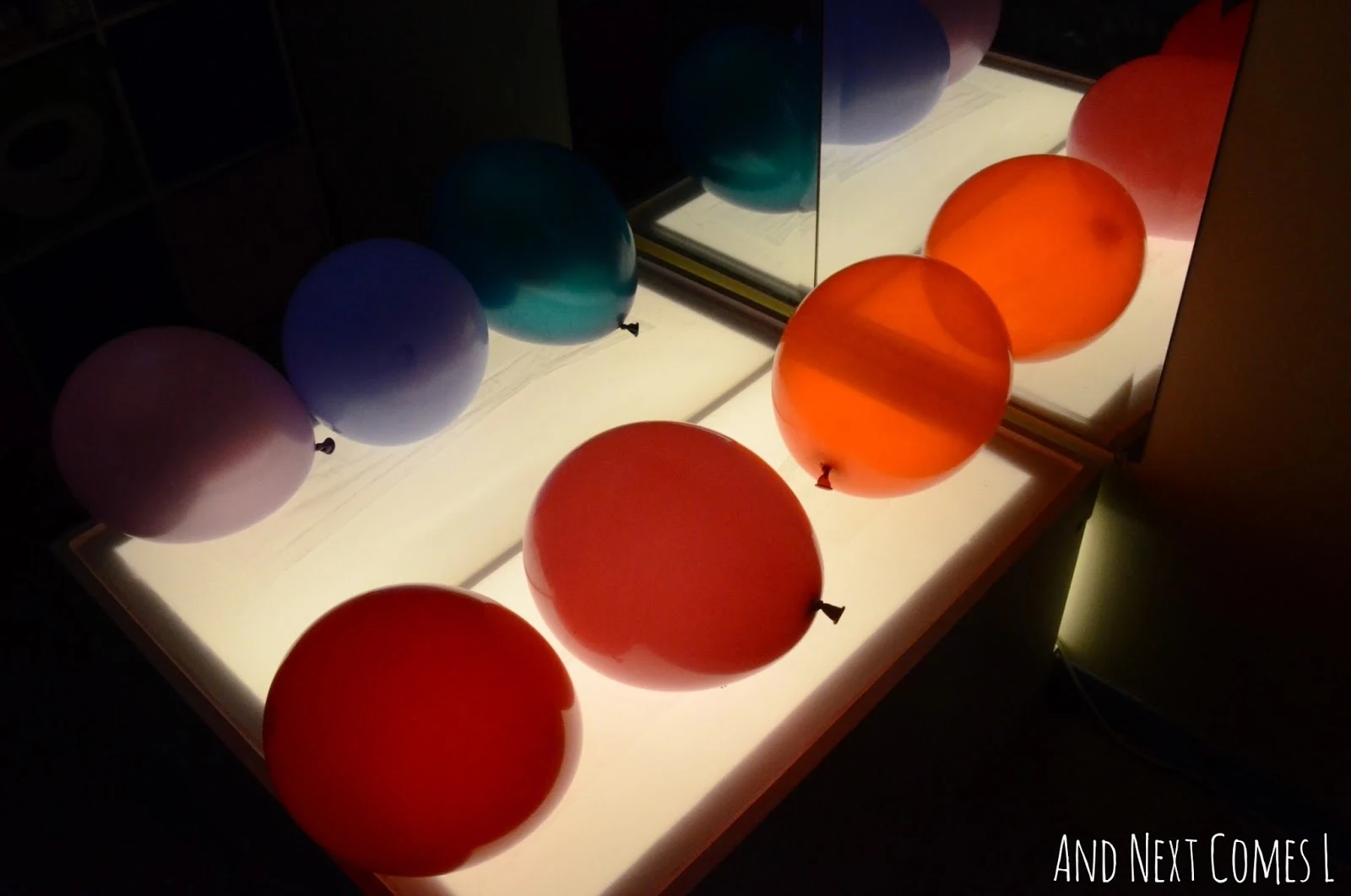 Balloons on a sticky light table from And Next Comes L
