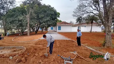 Acertando a terra para a execução da rua com o calçamento com pedras tipo de piso com pedrisco compactado com as guias de pedra, com pedra folheta, em rua da entrada da sede da fazenda em Atibaia-SP e a execução do paisagismo.