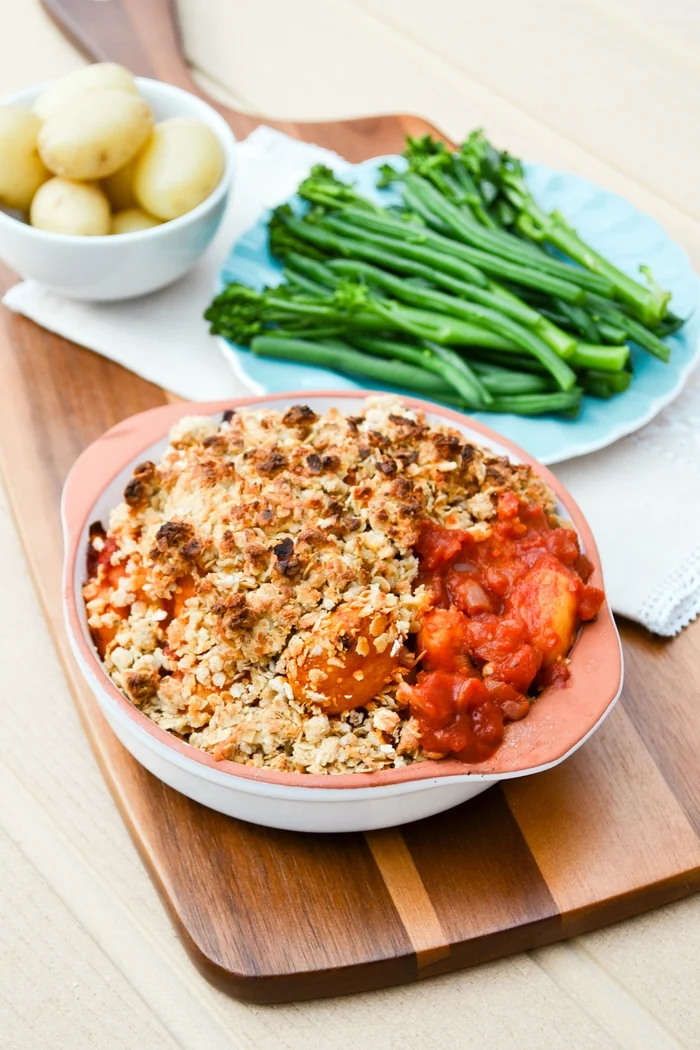 Vegan Tomato Gnocchi Bake with Cheesy Oat Crumble. An easy veggie family bake made with a fresh tomato sauce, gnocchi and a cheesy crumble topping. Serve with baby potatoes and vegetables. www.tinnedtomatoes.com
