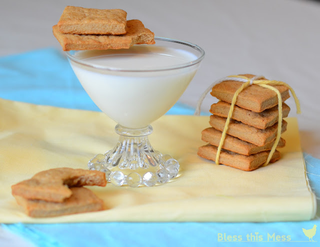 Graham Crackers sitting next to a glass of milk on a yellow cloth.