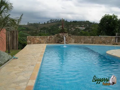 Construção do muro de pedra rústico com a construção da piscina de vinil com cascata de pedra e a bica d'água de madeira, o piso de pedra na piscina com pedra São Tomé tipo caco em sítio em Mairiporã-SP.