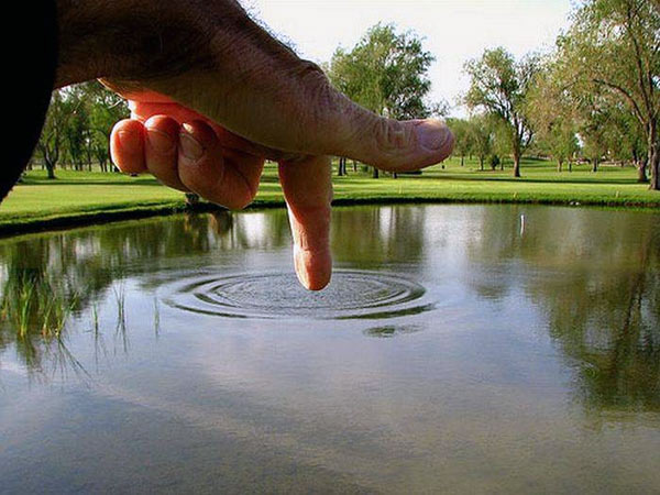 Küçük bir göldeki suya dokunan büyük bir el