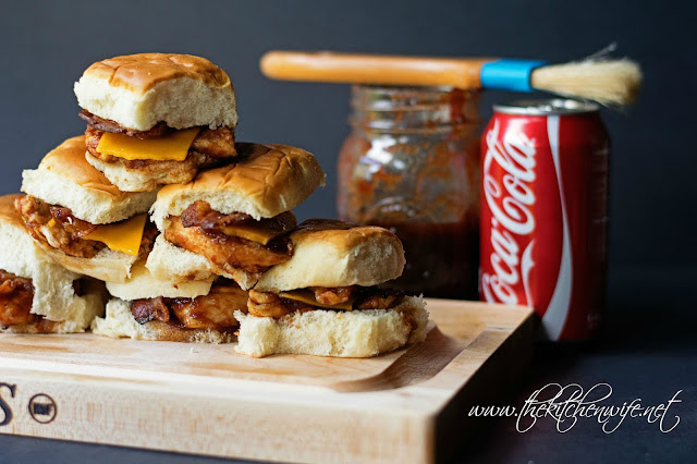 The Finished BBQ Chicken Sliders on a wood cutting board with the BBQ sauce in the