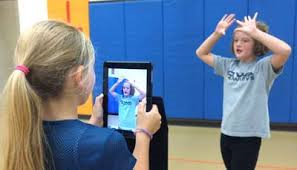 A girl videoing another learning how to set a volleyball