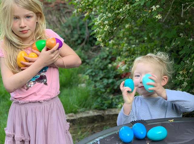 Sisters with lots of plastic eggs after collecting them from around the garden