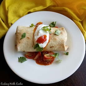 These fun baked chimichangas have a crisp golden exterior and are stuffed with eggs, cheese, potato and ham. They are ready in about 30 minutes and will have them all satisfied! baked breakfast chimichange served on plate with sour cream, salsa, cilantro and chopped tomatoes on top