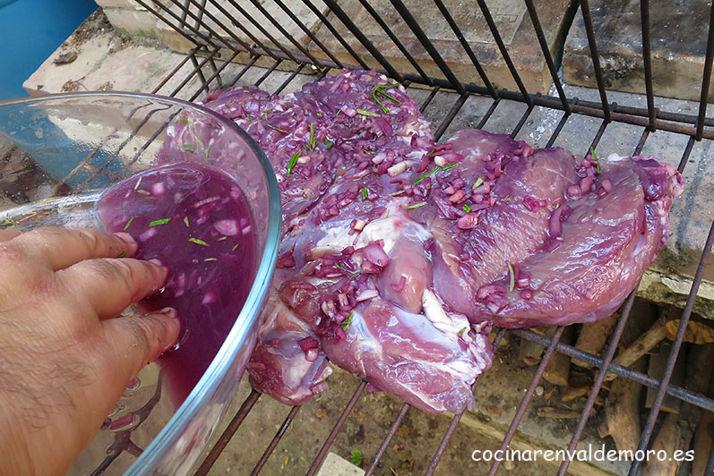 Poniendo la pierna de cordero en la parrilla con la marinada