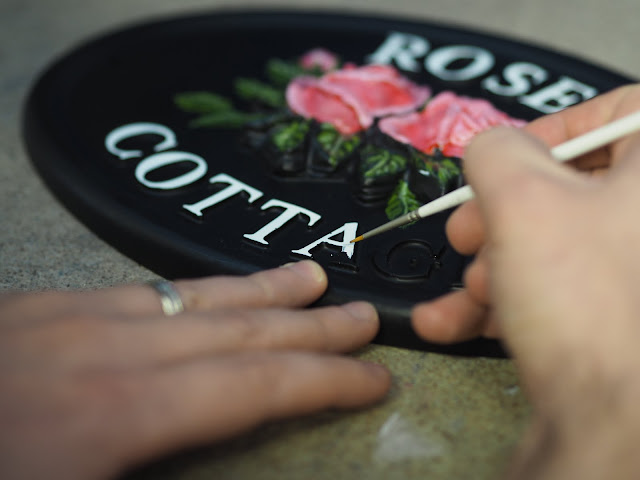 village green handpainting a house sign 