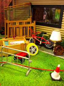 One-twelfth scale miniature scene of garage-sale items outside a garage.