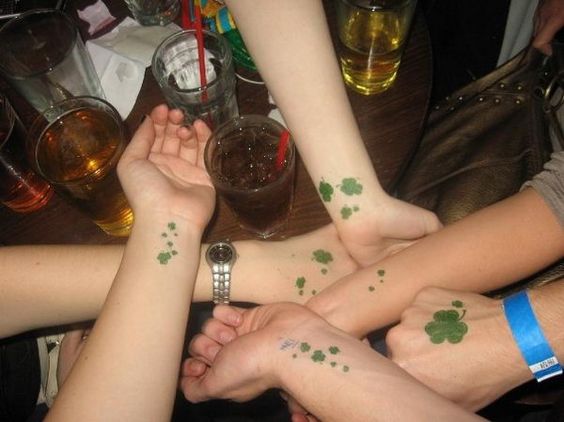 grupo de chicas juntando las manos, llevan tatuajes de treboles