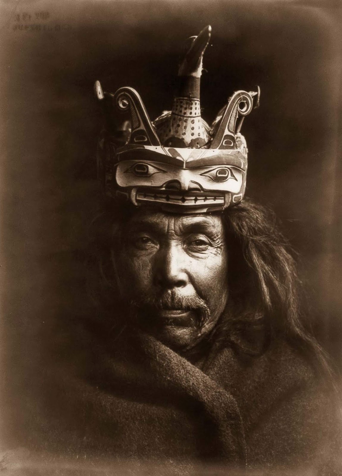 A Kwakiutl man wearing a mask depicting a man transforming into a loon. 1914.